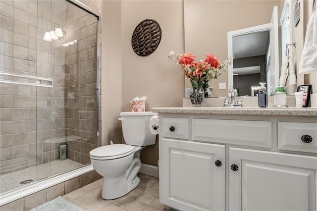 full bath featuring toilet, a stall shower, vanity, baseboards, and tile patterned floors