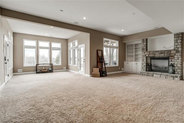 unfurnished living room featuring carpet floors, a stone fireplace, recessed lighting, and baseboards