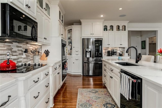 kitchen with dark wood finished floors, white cabinets, a sink, and black appliances