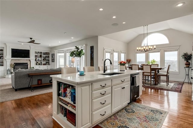 kitchen with black dishwasher, a glass covered fireplace, a sink, and a wealth of natural light