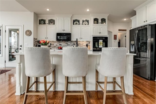 kitchen with black appliances, white cabinets, and light wood finished floors