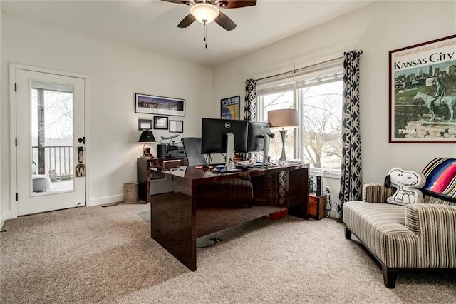 carpeted office space featuring baseboards and a ceiling fan