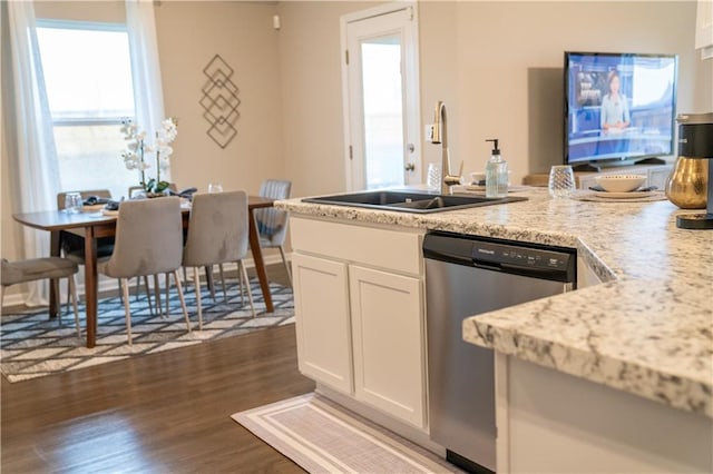 kitchen with dark wood-type flooring, light stone countertops, stainless steel dishwasher, white cabinetry, and a sink