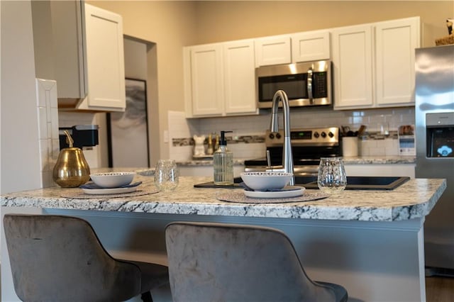 kitchen featuring white cabinetry, appliances with stainless steel finishes, and decorative backsplash