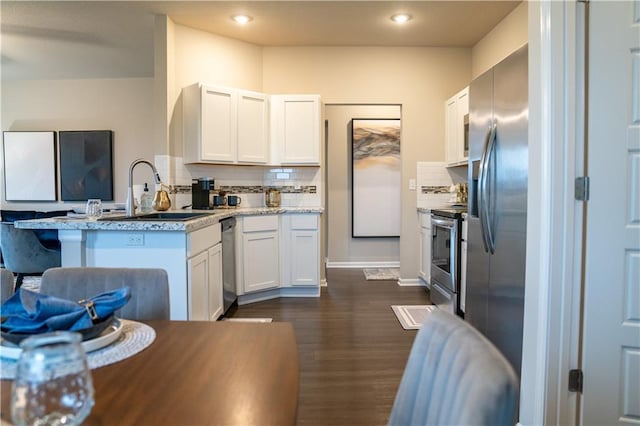 kitchen with stainless steel appliances, a sink, a peninsula, and decorative backsplash