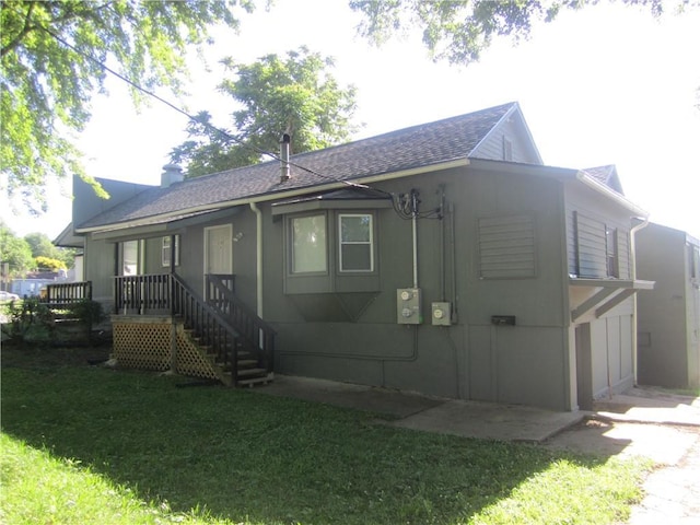 exterior space with a shingled roof and a front yard