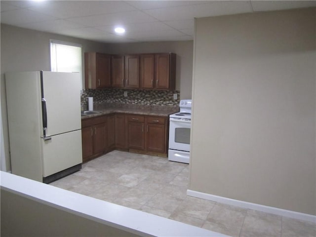 kitchen featuring white appliances, baseboards, decorative backsplash, and a drop ceiling