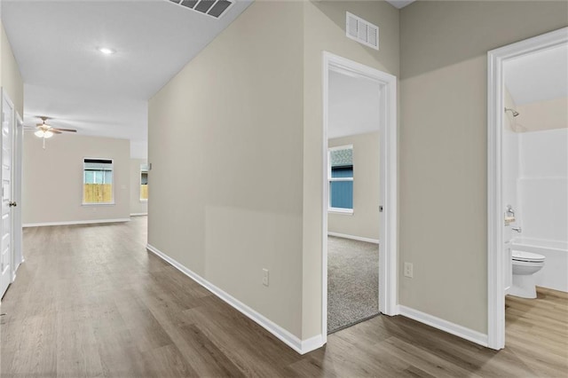 hallway with visible vents, baseboards, and wood finished floors