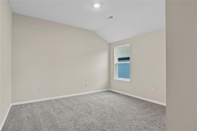 carpeted empty room with baseboards, visible vents, and vaulted ceiling