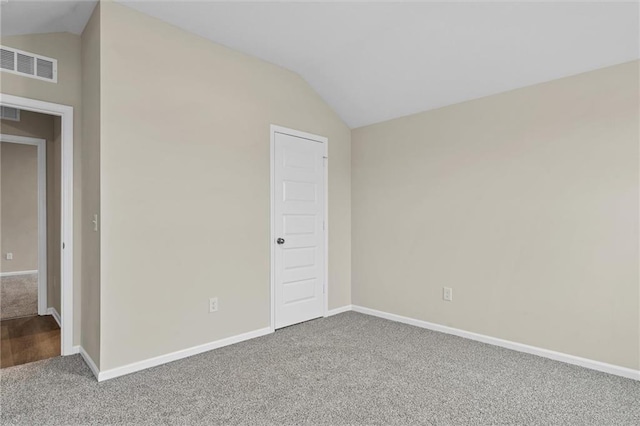 spare room with carpet flooring, vaulted ceiling, visible vents, and baseboards