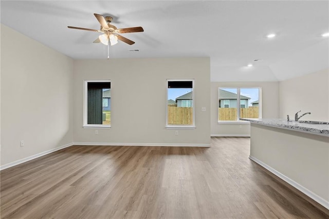 unfurnished living room featuring baseboards, visible vents, ceiling fan, wood finished floors, and a sink