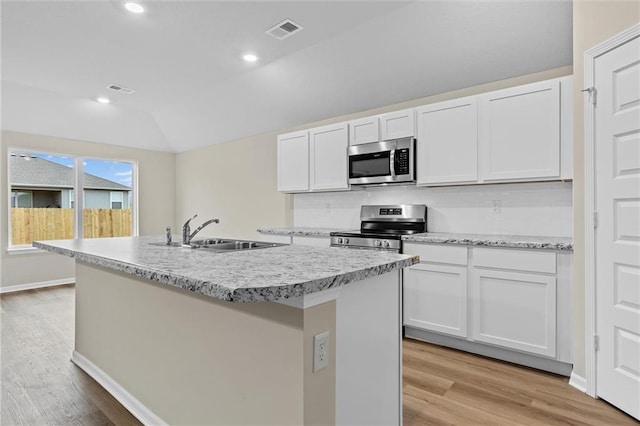 kitchen featuring visible vents, white cabinets, appliances with stainless steel finishes, a sink, and backsplash