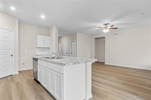 kitchen with light wood-style flooring, white cabinets, a kitchen island with sink, a sink, and dishwasher