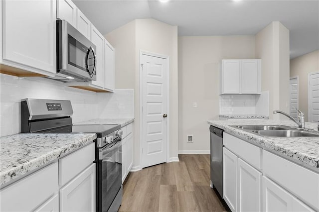 kitchen featuring stainless steel appliances, white cabinets, a sink, and light wood-style flooring