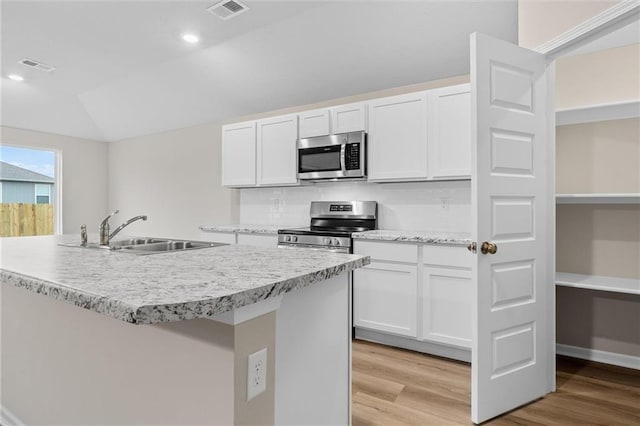 kitchen with light wood-style flooring, stainless steel appliances, a sink, visible vents, and white cabinetry