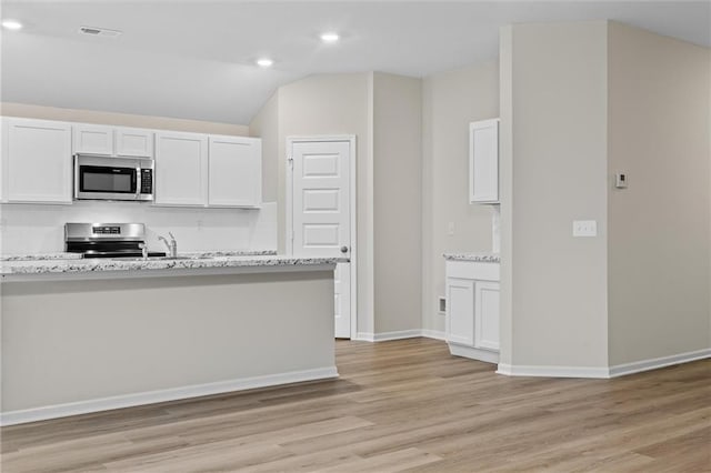 kitchen with light wood finished floors, visible vents, baseboards, stainless steel appliances, and white cabinetry