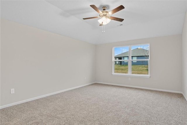 carpeted spare room with a ceiling fan, a raised ceiling, visible vents, and baseboards