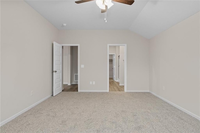 unfurnished bedroom with visible vents, baseboards, carpet, a walk in closet, and vaulted ceiling