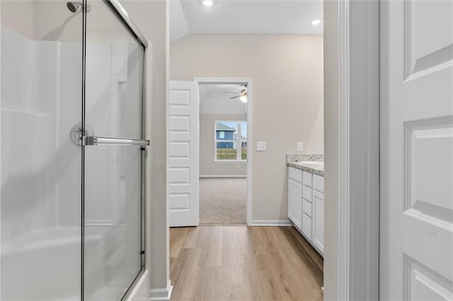 full bathroom featuring vaulted ceiling, a stall shower, wood finished floors, and vanity