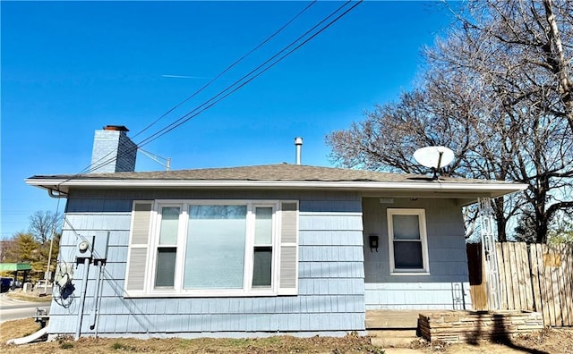 view of property exterior featuring a chimney and fence