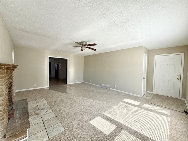 unfurnished living room featuring baseboards, visible vents, ceiling fan, a textured ceiling, and a fireplace