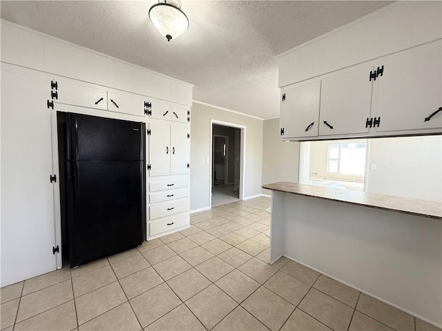 kitchen featuring light tile patterned flooring, ornamental molding, a textured ceiling, and freestanding refrigerator