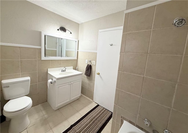 full bathroom with toilet, tile patterned floors, a textured ceiling, vanity, and tile walls