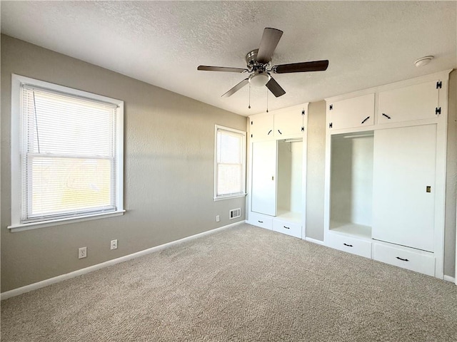 unfurnished bedroom featuring a textured ceiling, carpet floors, visible vents, and baseboards