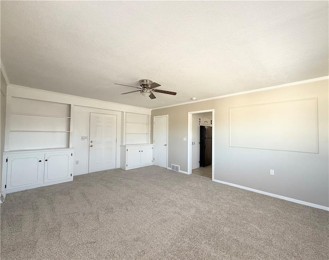 unfurnished bedroom with carpet floors, visible vents, ornamental molding, freestanding refrigerator, and a textured ceiling