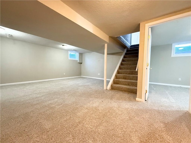 basement with carpet floors, a textured ceiling, baseboards, and stairs