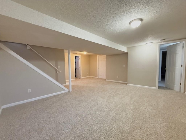 finished basement featuring light carpet, stairway, a textured ceiling, and baseboards