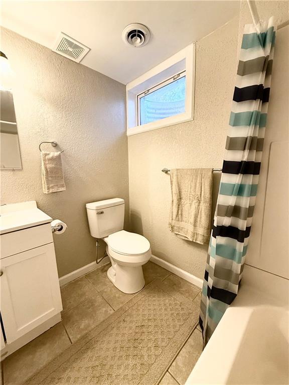 bathroom with visible vents, a textured wall, vanity, and toilet