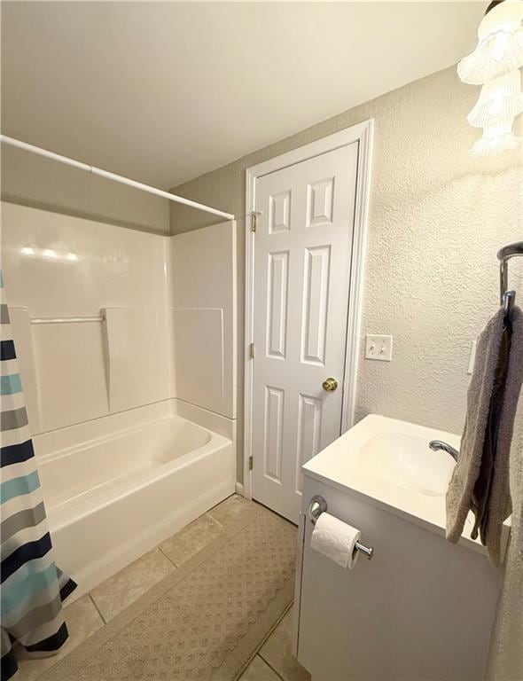 full bathroom featuring a textured wall, shower / bathtub combination with curtain, vanity, and tile patterned floors