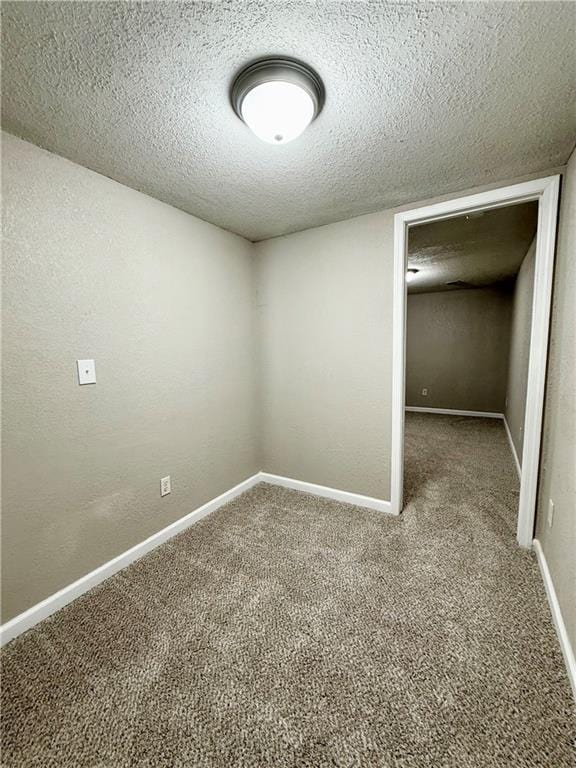 interior space with a textured ceiling, carpet flooring, and baseboards