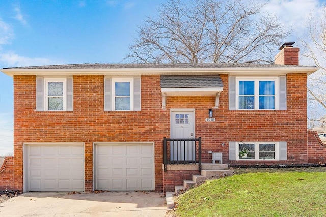 raised ranch with an attached garage, brick siding, driveway, a chimney, and a front yard