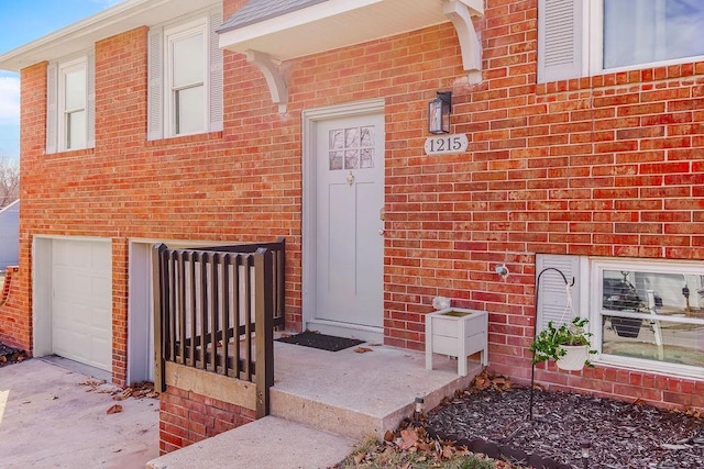 doorway to property with driveway, brick siding, and an attached garage