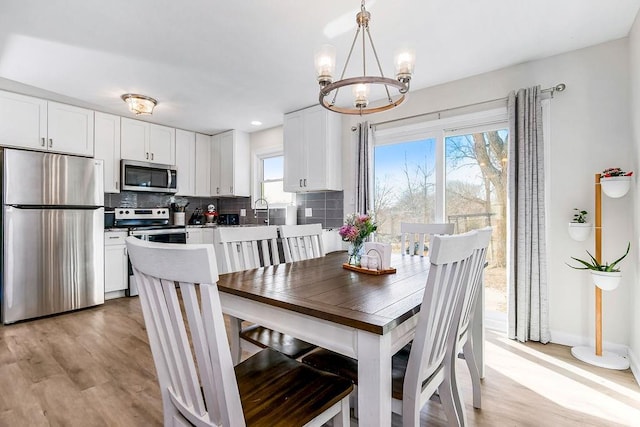 dining room featuring a notable chandelier, light wood-style flooring, and baseboards