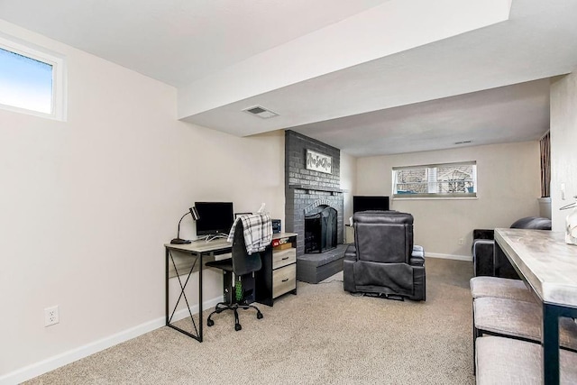 office featuring a brick fireplace, visible vents, baseboards, and carpet flooring