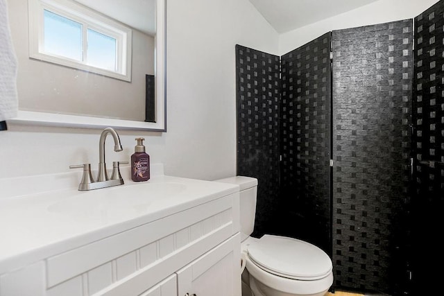 bathroom with tiled shower, vanity, and toilet