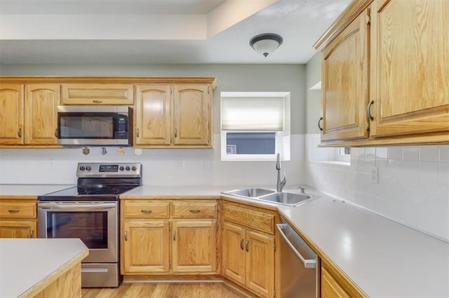 kitchen with light wood-type flooring, stainless steel appliances, a sink, and light countertops