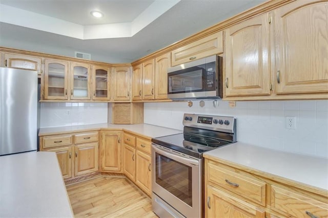 kitchen with stainless steel appliances, visible vents, light countertops, light brown cabinetry, and light wood finished floors