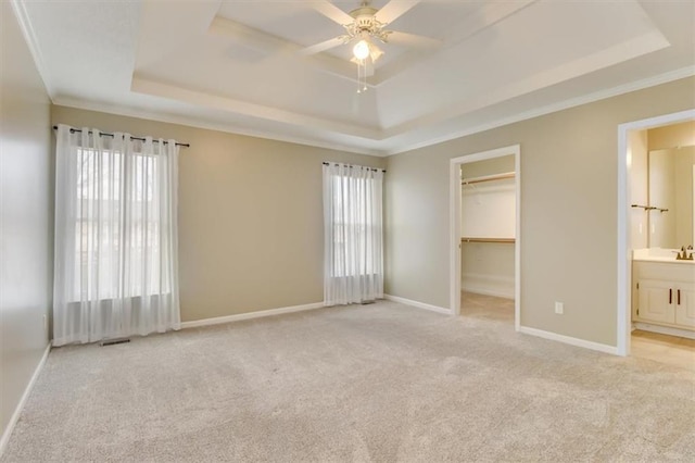 unfurnished bedroom with a tray ceiling, light colored carpet, and baseboards