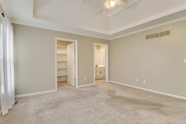 unfurnished bedroom featuring light carpet, baseboards, visible vents, and a walk in closet