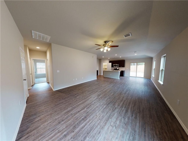 unfurnished living room with dark wood-type flooring, visible vents, and baseboards