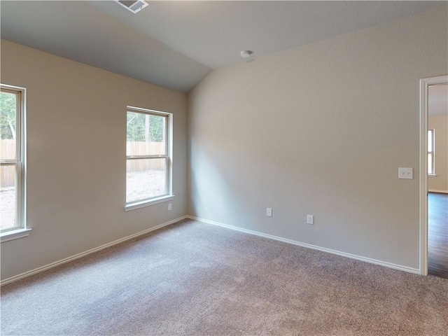 carpeted empty room with vaulted ceiling and baseboards