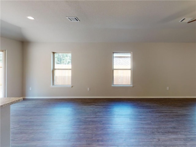 unfurnished room featuring recessed lighting, dark wood finished floors, visible vents, and baseboards