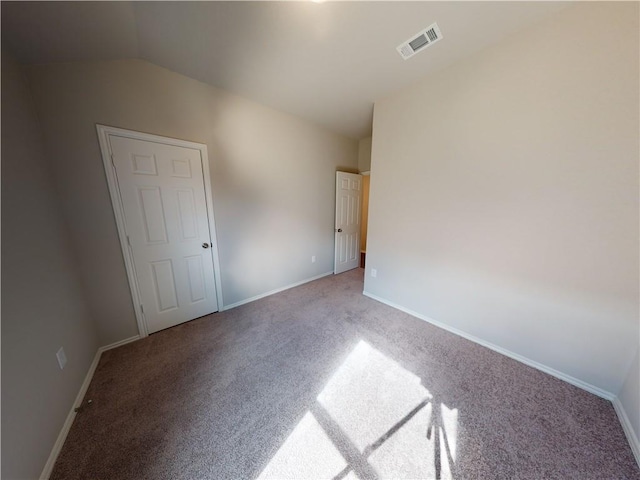 unfurnished bedroom with vaulted ceiling, carpet flooring, visible vents, and baseboards