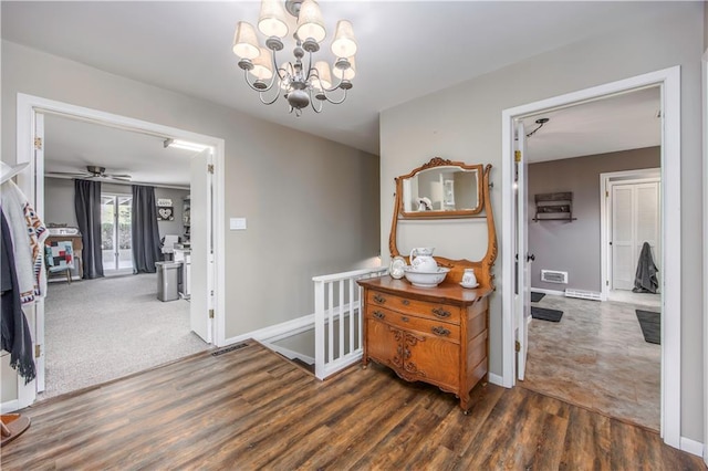 hallway with a notable chandelier, wood finished floors, visible vents, and baseboards