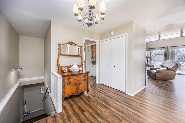 entrance foyer with baseboards, a notable chandelier, and wood finished floors