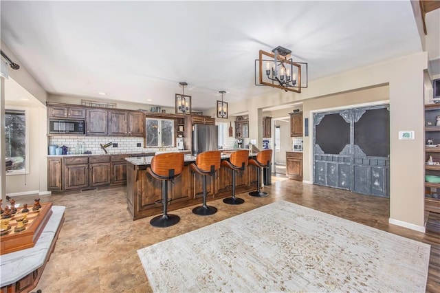 kitchen with a large island, backsplash, freestanding refrigerator, a breakfast bar area, and built in microwave